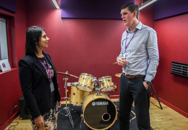 Picture of Sara Khan talking to a Poplar HARCA employee, standing in front of a drum kit